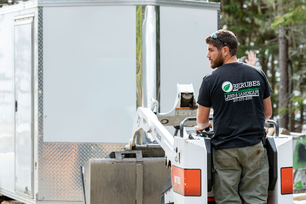 man-operating-machine-in-front-of-enclosed-5-6-wide-cargo-trailer